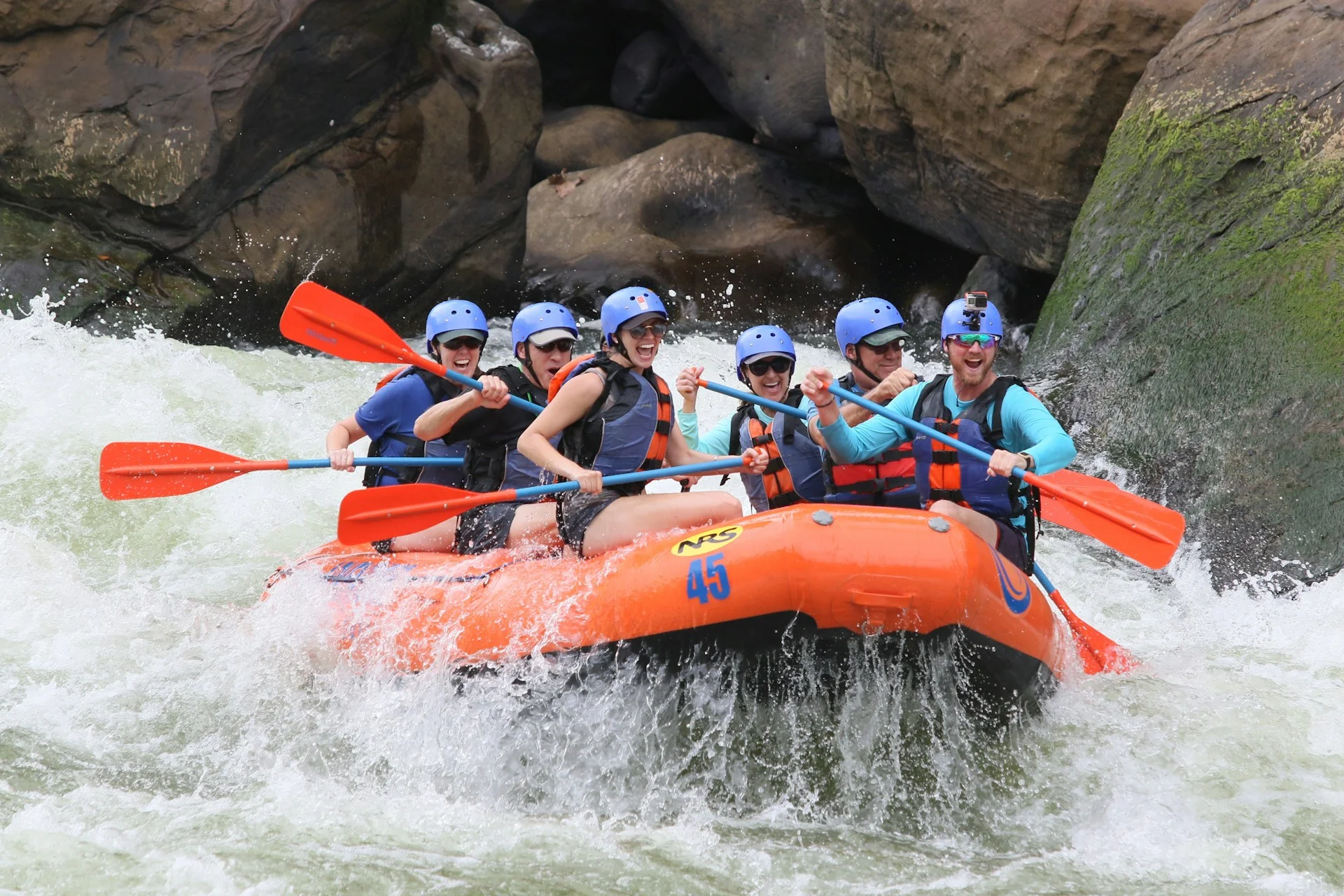 Peserta rafting dengan helm dan pelampung di perahu karet