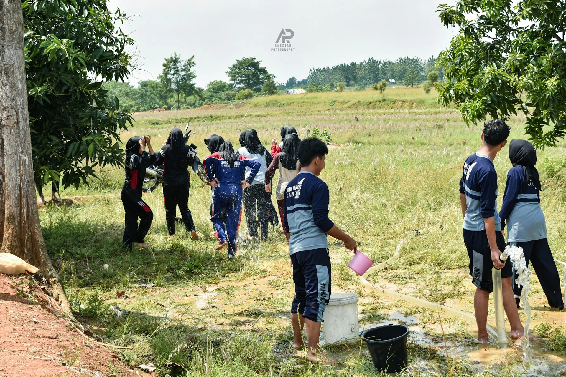 Permainan kelompok dengan ember dan air di lapangan