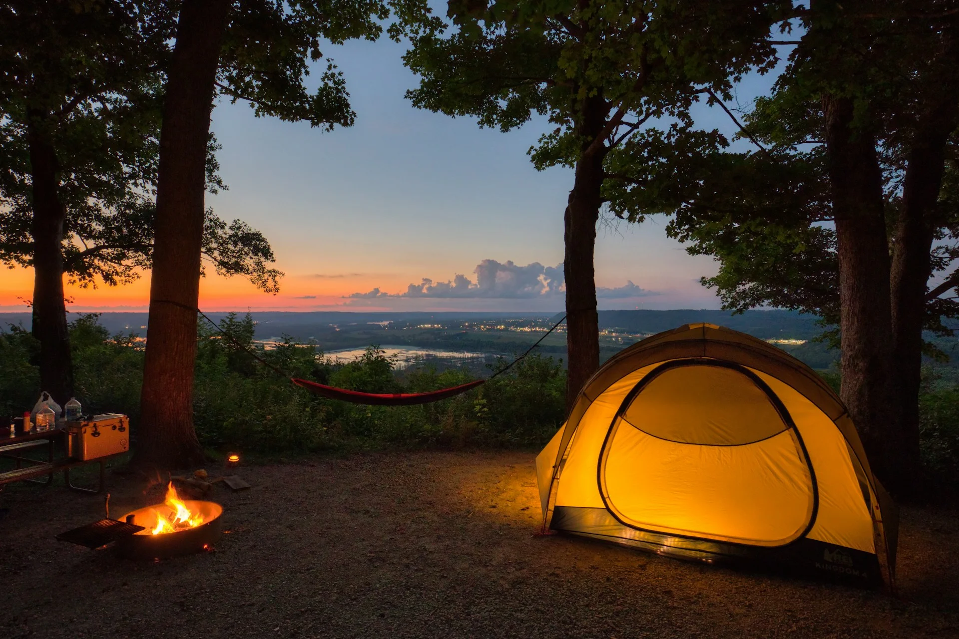 Tenda camping di area pepohonan saat senja