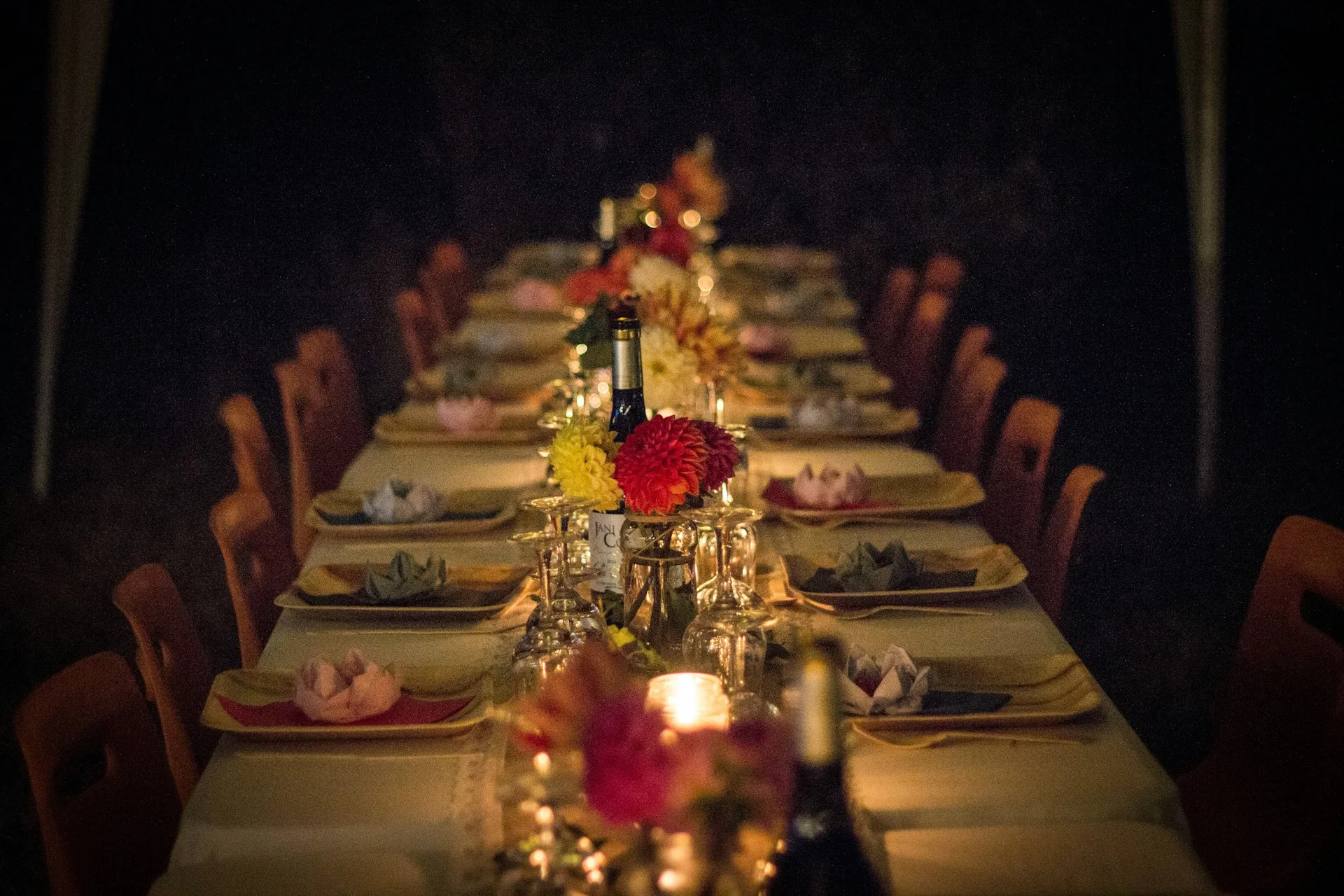 A long dining table set for a dinner party with flowers and candles