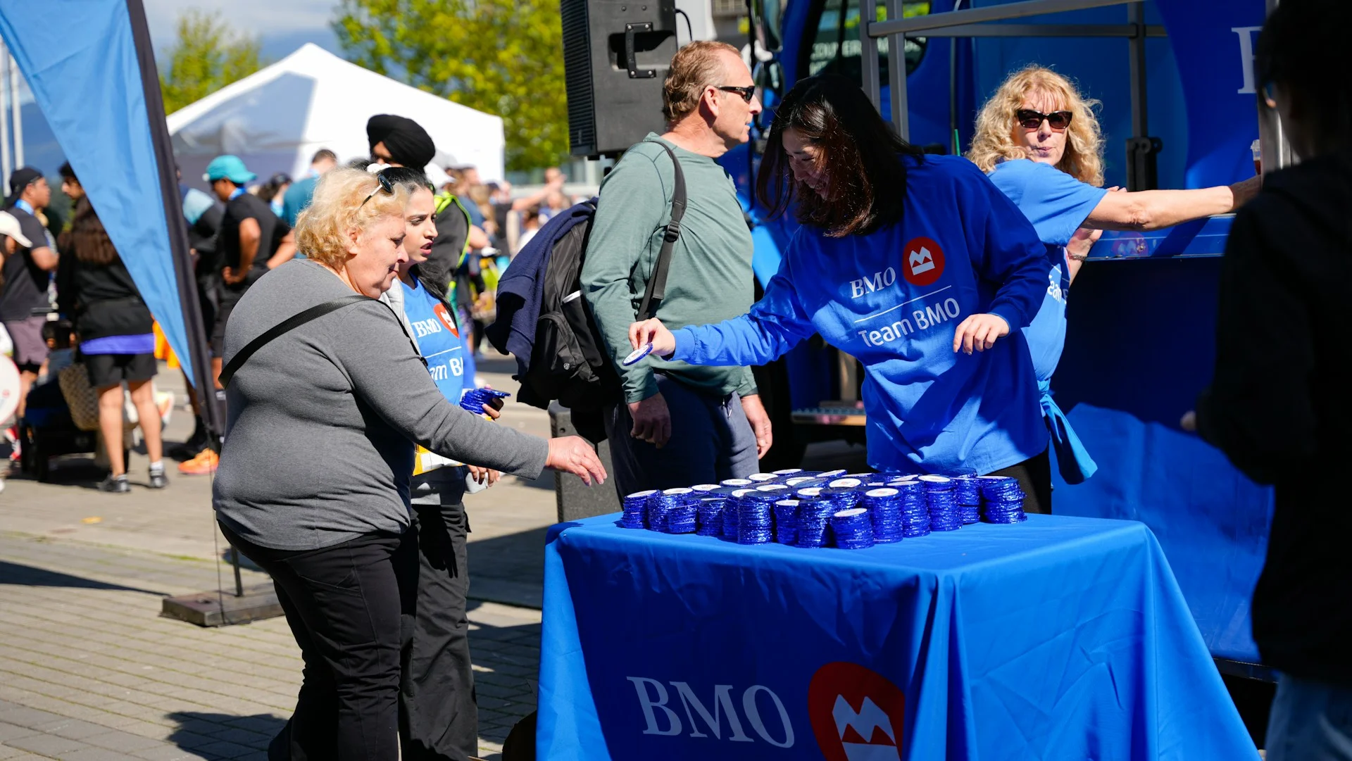 People receiving drinks from a table at an outdoor event