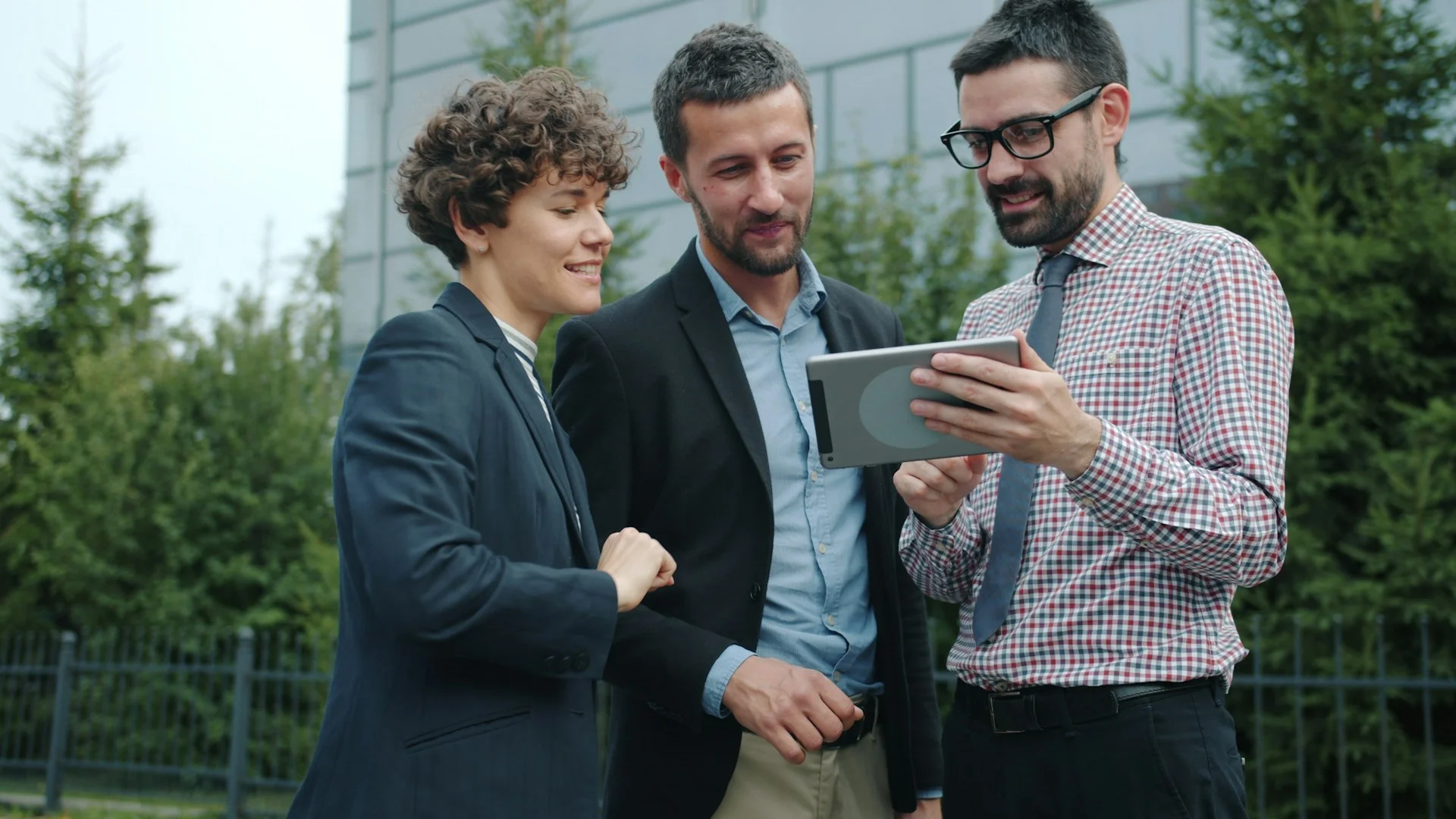 Three business people looking at a tablet outside